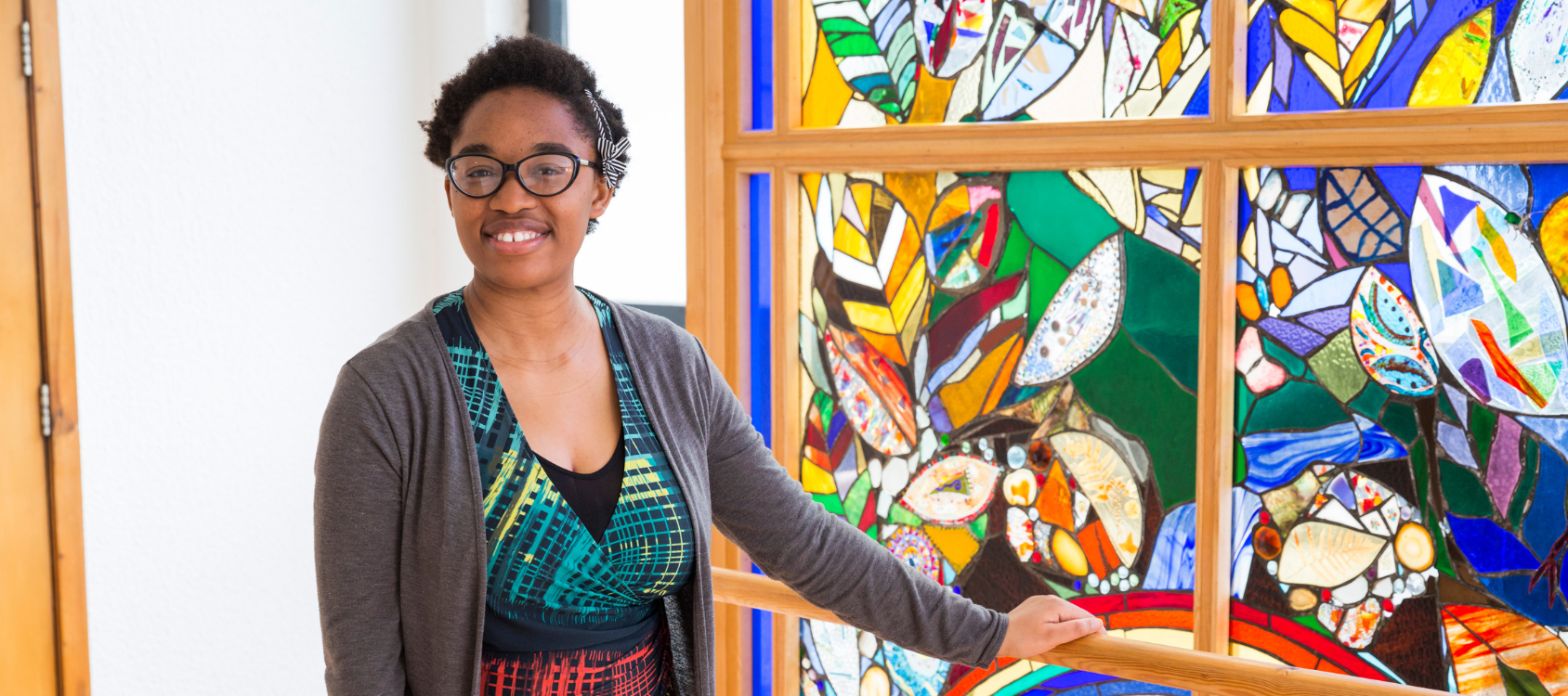 A student in front of a stained glass window