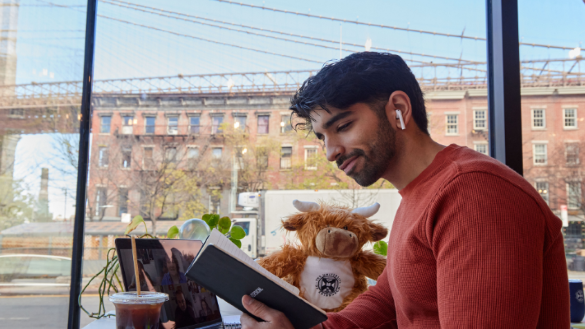 A student based in New York reads from a University branded notebook