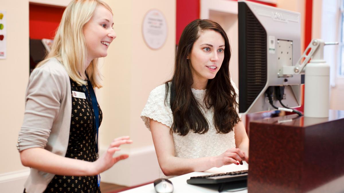 Two women talking and looking at a computer screen