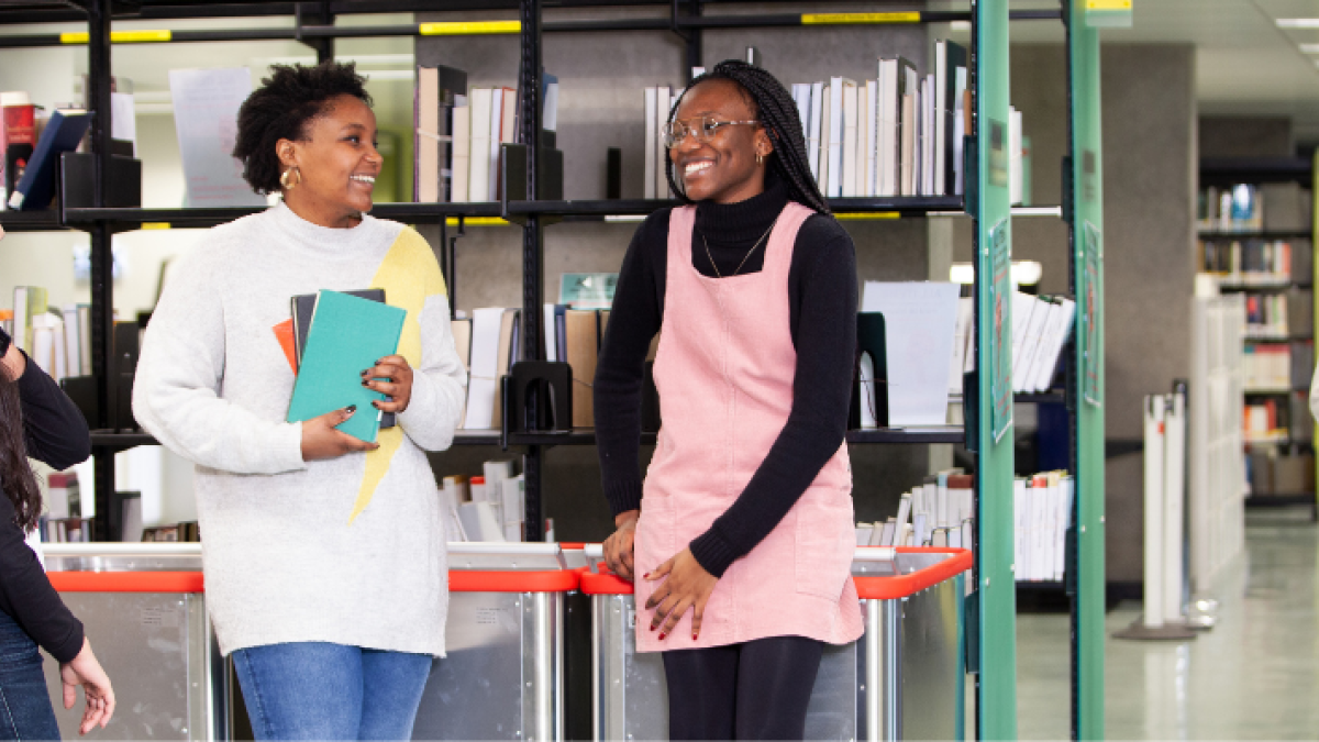 A group of laughing students in front of a bookcase