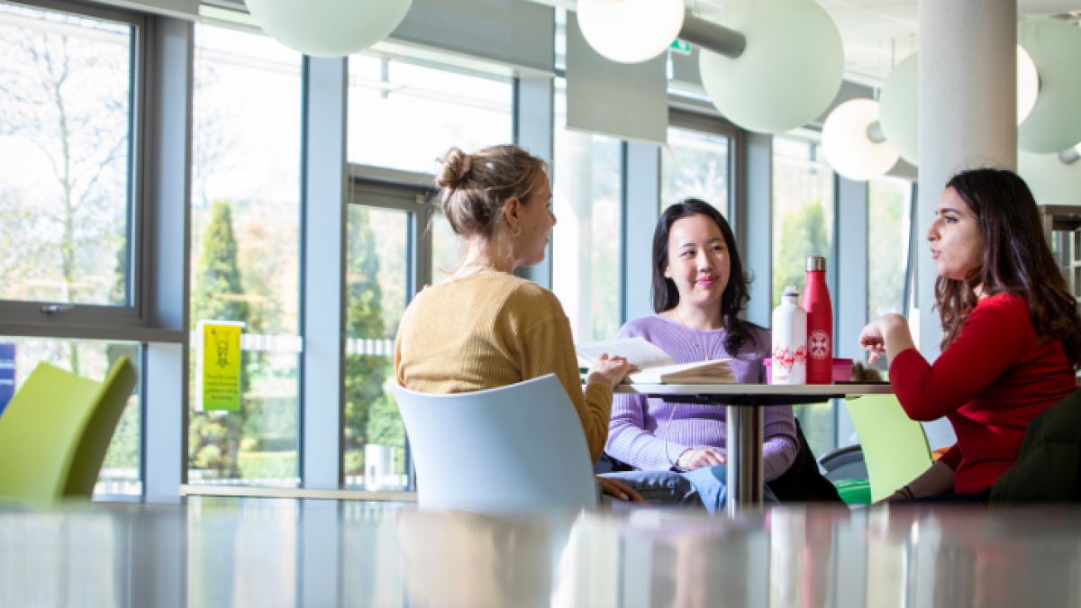 Three female students chat in a cafe