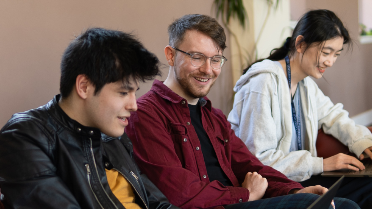 Three happy students looking at their computer screens