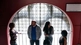 The silhouette of three people talking on a staircase in front of a window