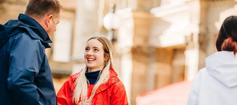 A young open day volunteer in a red coat talks to a visitor